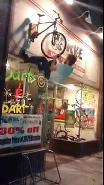 Un gars saoul veut monter sur un vélo qui sert d'enseigne à un magasin