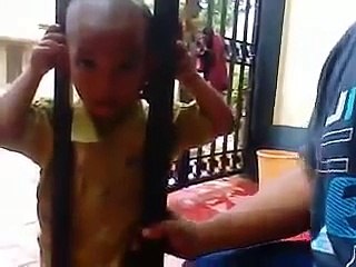 Un gamin a la tête coincée dans un portail. Son père vient l'aider...
