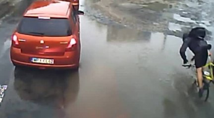 Un homme en vélo finit la tête la première dans une flaque d'eau
