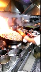 A chef is cooking in a wok for 60 people (China)