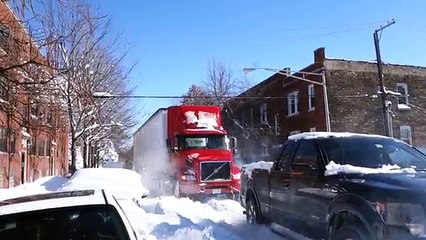 Un pick-up remorque un camion bloqué dans la neige