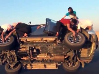 Young men change tires of a car in motion
