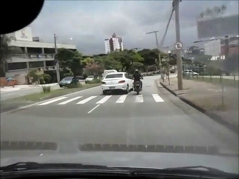 Motociclista nervoso bate em carro com o pé e cai no asfalto