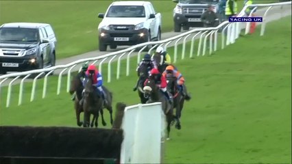 Un jockeysaute une haie à côté de son cheval