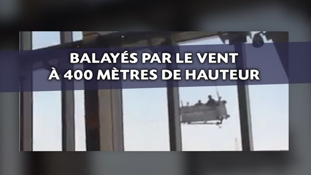 Deux laveurs de carreaux balayés par le vent en haut d'un gratte-ciel