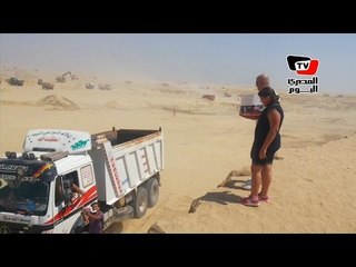 مواطن وابنته يوزعان مياه غازية على العاملين بقناة السويس الجديدة