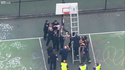 Un homme torse nu armé d’un marteau est coincé à un panier de basket (Seattle)