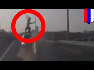 Motocyklista uderza w tył samochodu i ląduje na nogach na jego dachu.