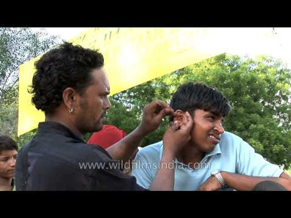 Street-side ear cleaner makes client scowl, in Delhi