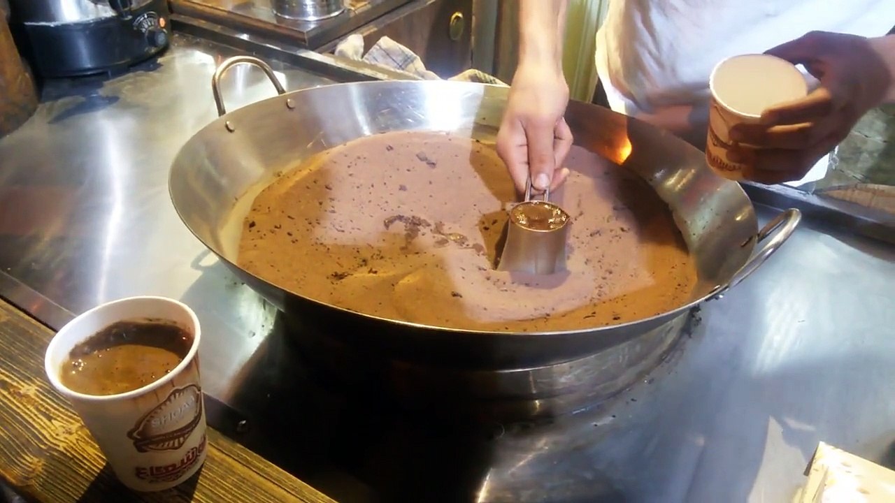 Un vendeur fait du café à l'infini dans un bol rempli de sable