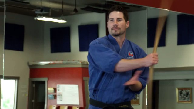 Man in karate gear practicing bow staff weapon moves