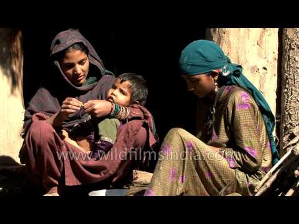 Kashmiri women sit outside thier wooden hut