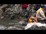 Woman carries out ablutions below slow motion Himalayan waterfall