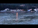 Foreign tourists sit on the banks of Ganga River in Rishikesh