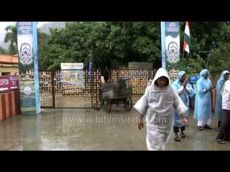 People protect themselves from rain using plastic bags and rain coats, Rishikesh