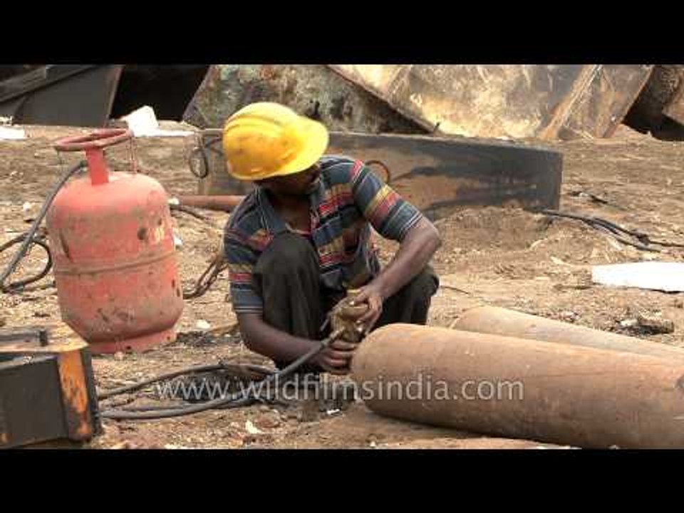 Indian worker checks gas cylinders at a ship breaking yard in Alang - India