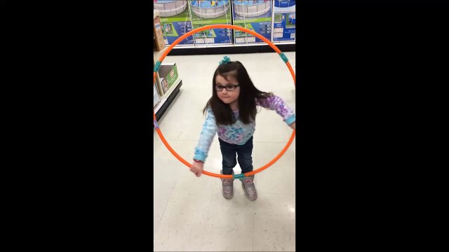 Une petite fille essaie de faire du hula hoop. Trop mignon