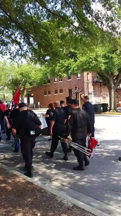 Un homme joue du tuba pour se moquer des membres du Ku Klux Klan qui manifestent dans la rue