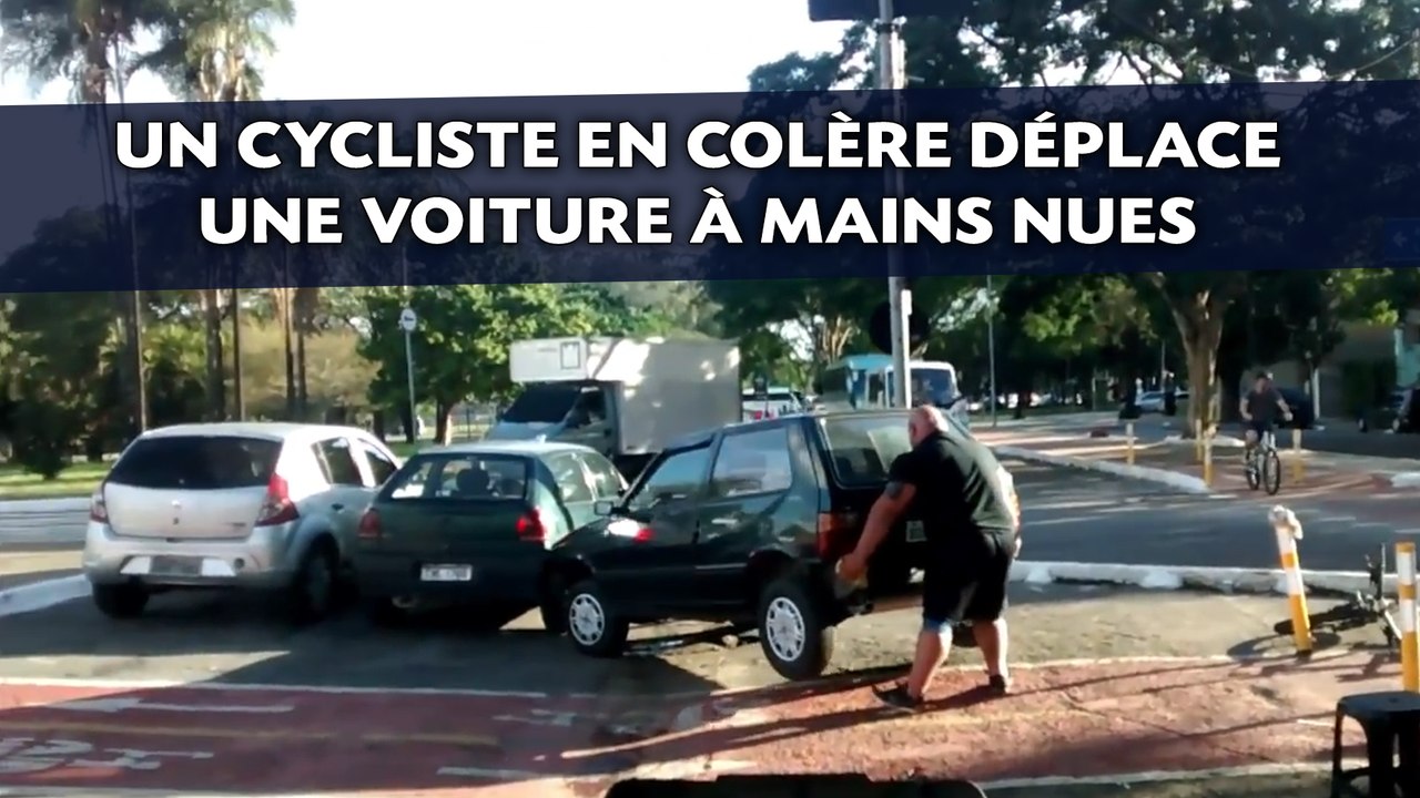 Un cycliste en colère déplace une voiture à mains nues