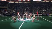 Un joueur de football américain fait un grand écart au milieu des pompom girls