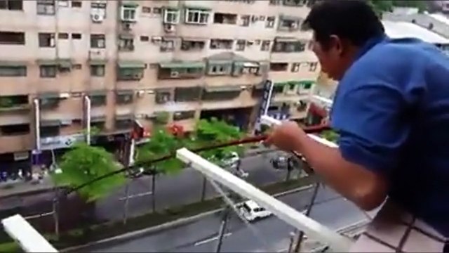 Un homme pêche un poisson depuis son balcon