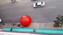 Giant red Ball rolls down the street over Cars in Toledo