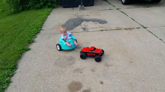 Un bébé dans son pot tiré par une voiture télécommandée