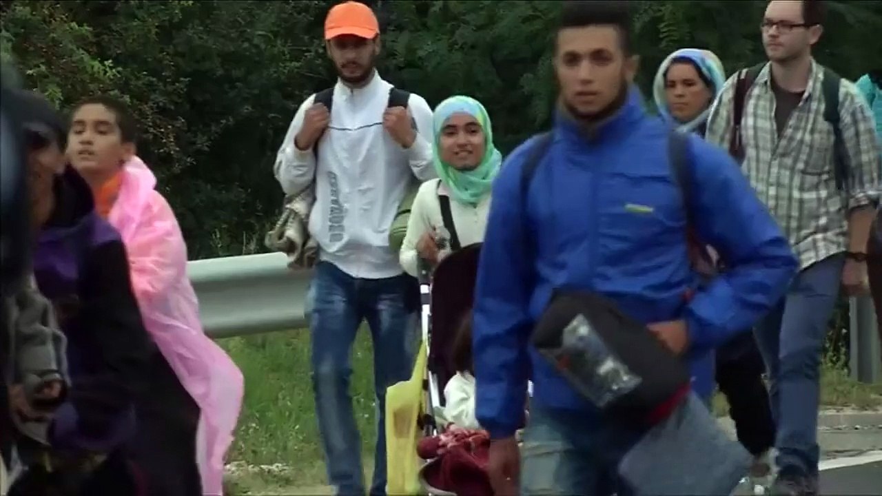 Migrants chant "We want buses" as they walk towards Austria