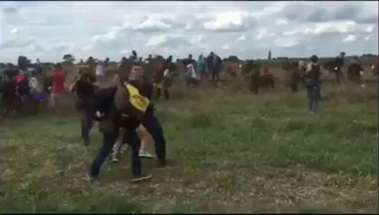 A Hungarian camerawoman trips refugees who are running from police