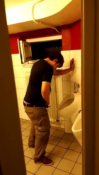 Un mec bourré essaie d'uriner aux toilettes