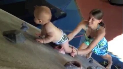 Baby clambers up indoor climbing wall