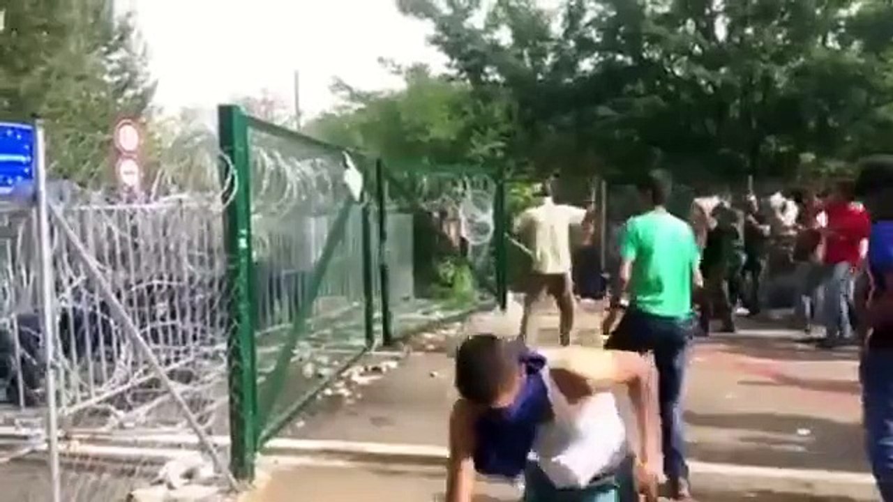 des migrants essayant violemment à ouvrir  les portes situées au frontière Serbia-Hungary