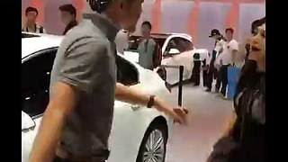 Woman wants man to buy white car for her at auto show