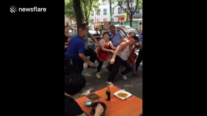 Man calmly finishes noodles as street brawl breaks out around him