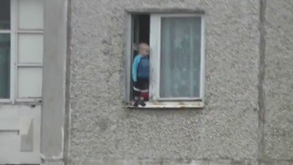 Un bébé joue sur le rebord d'une fenêtre au 8ième étage
