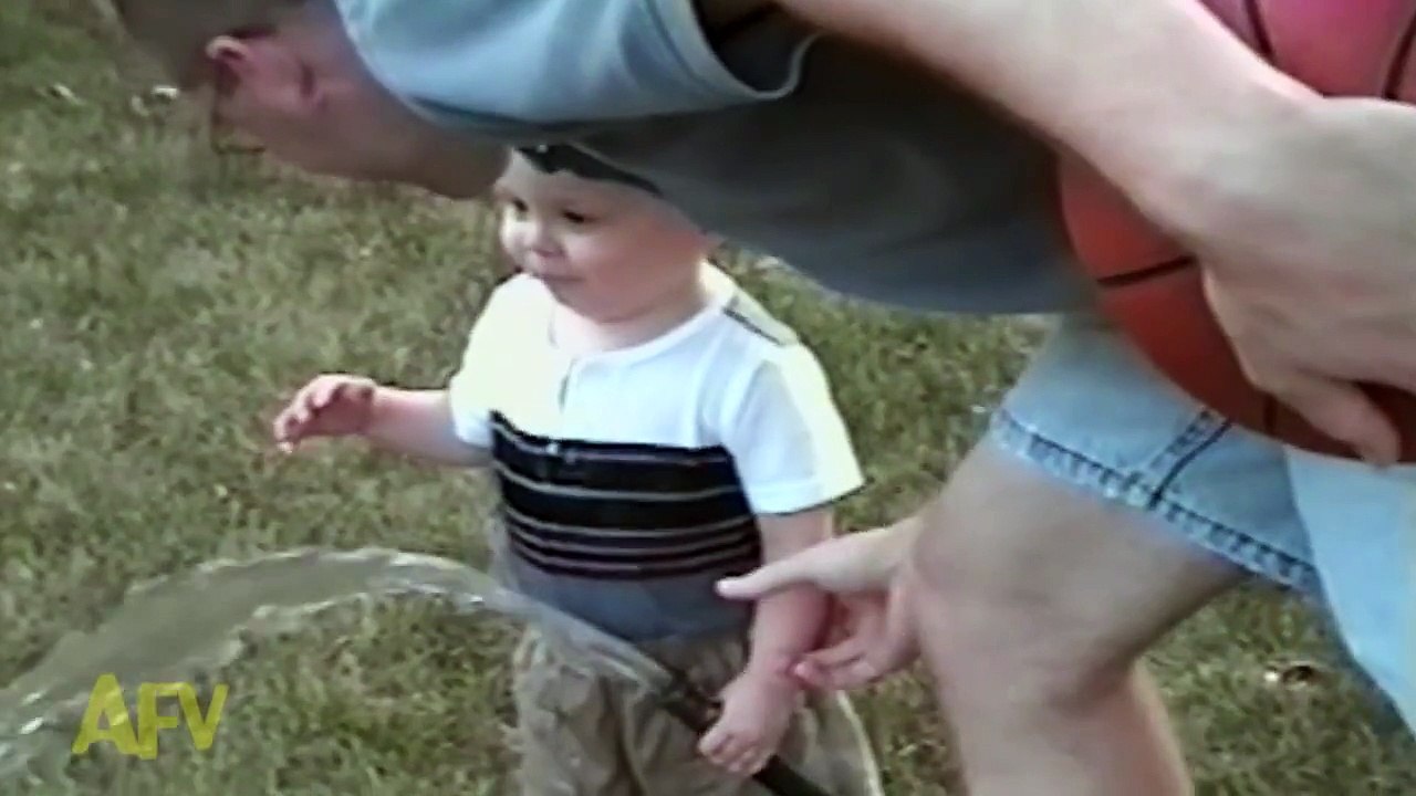 Adorable baby boy attempts to drink water from a hose