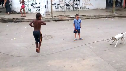 Un chien tient une corde à sauter pour faire jouer des enfants