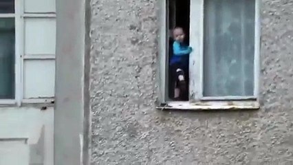 Un enfant s’amuse sur le bord d’une fenêtre au 8ème étage