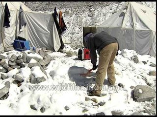 Mountaineer cleans snow with shovel at Base camp