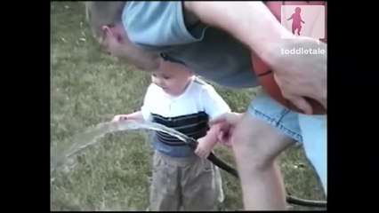 Adorable baby boy drinks from the hose to stay cool