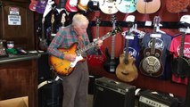 81-year-old man checks the guitar before buying