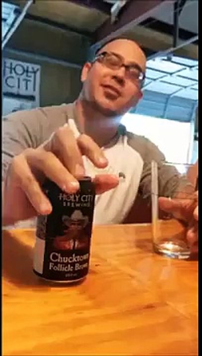 Bald guy pours a beer using his forehead