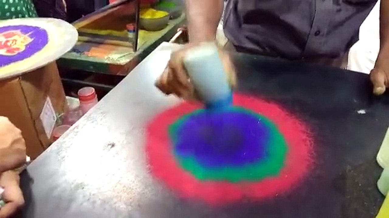 Un homme réalise un rangoli avec de la poudre de riz (Inde)