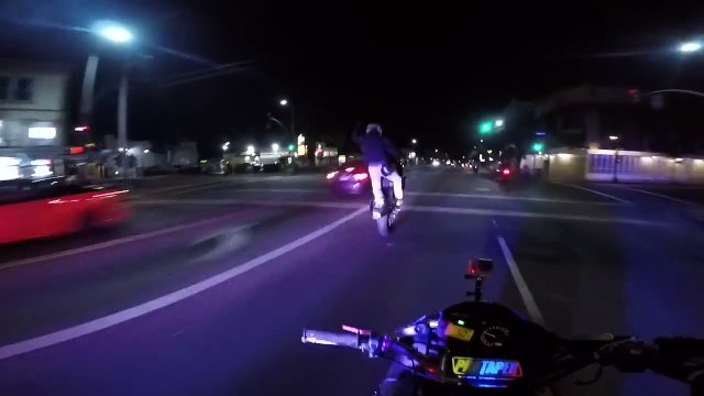 Il fait des figures sur sa moto en plein wheeling juste devant les flics