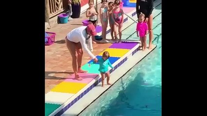 Une maître-nageuse pousse un bébé à l'eau