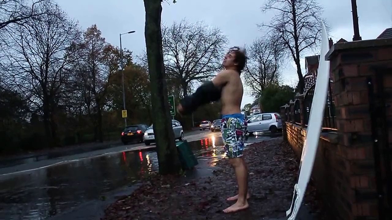 Un gars surfe sur un baril sous la pluie en pleine rue... Taré!