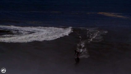 Guy rides an enormous wave on a skimboard