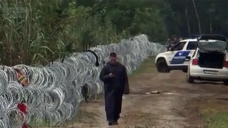 Syrian refugee crosses border while officer on his phone.