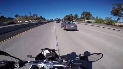 Un motard fait une blague à une fille se trouvant dans une voiture sur l'autoroute