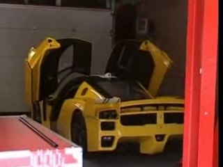 Ferrari FXX noire jaune et rouge stands